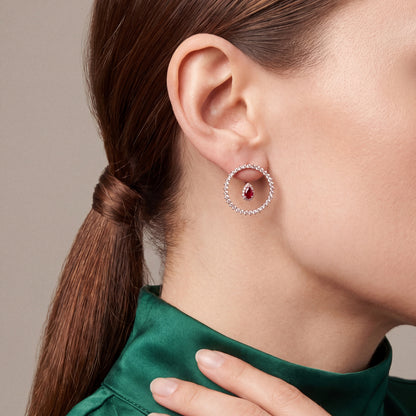 Ruby and natural diamond open circle earring in 14K rose gold, worn with an emerald silk high-collar blouse