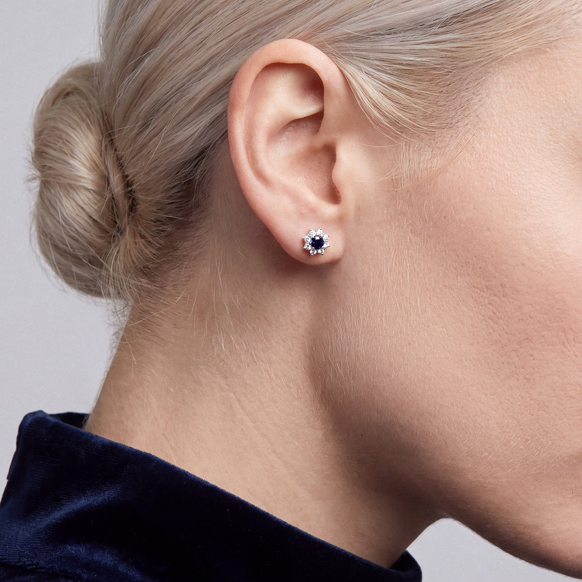 0.53 ct blue sapphire and diamond halo stud in 18K white gold, worn with a navy velvet high collar