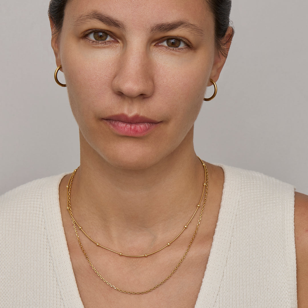 Gold satellite chain necklace worn on the neck