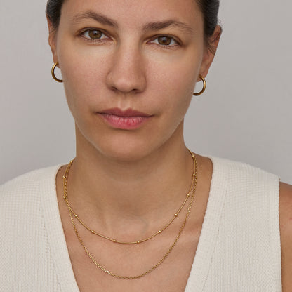 Gold satellite chain necklace worn on the neck