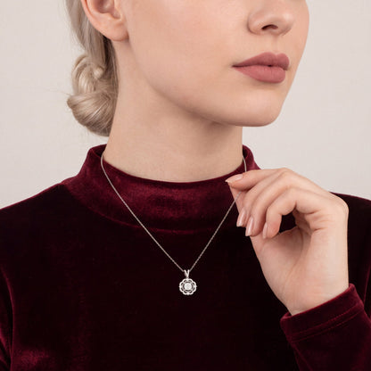 Woman in an oxblood velvet mock-neck top holding the chain of a natural diamond scalloped halo pendant necklace in 14K white gold