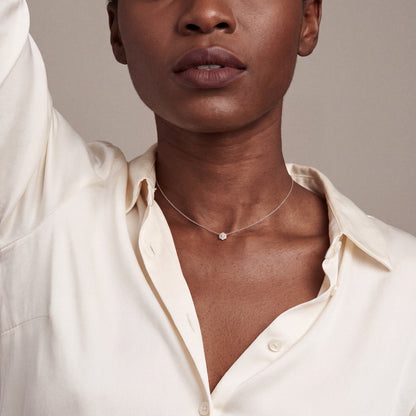 Model in an ivory silk shirt wearing the snowflake baguette natural diamond necklace in 14K solid white gold
