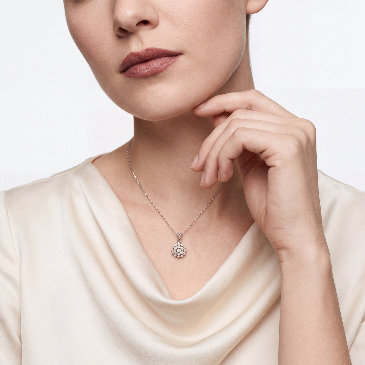 Woman in a cream silk cowl-neck blouse wearing the starburst natural diamond cluster pendant necklace in 14K solid white gold