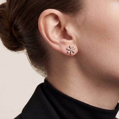 Woman in a black tuxedo blazer and high mock neck wearing a tapered baguette natural diamond flower stud earring in 18K rose gold