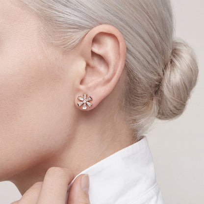 Woman in a white poplin shirt with a turned-up collar wearing a tapered baguette natural diamond flower stud earring in 18K rose gold
