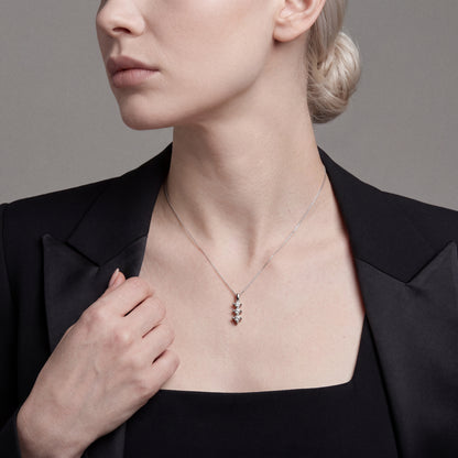 Woman in a black tuxedo jacket wearing the three-stone natural diamond star drop pendant necklace in 14K white gold
