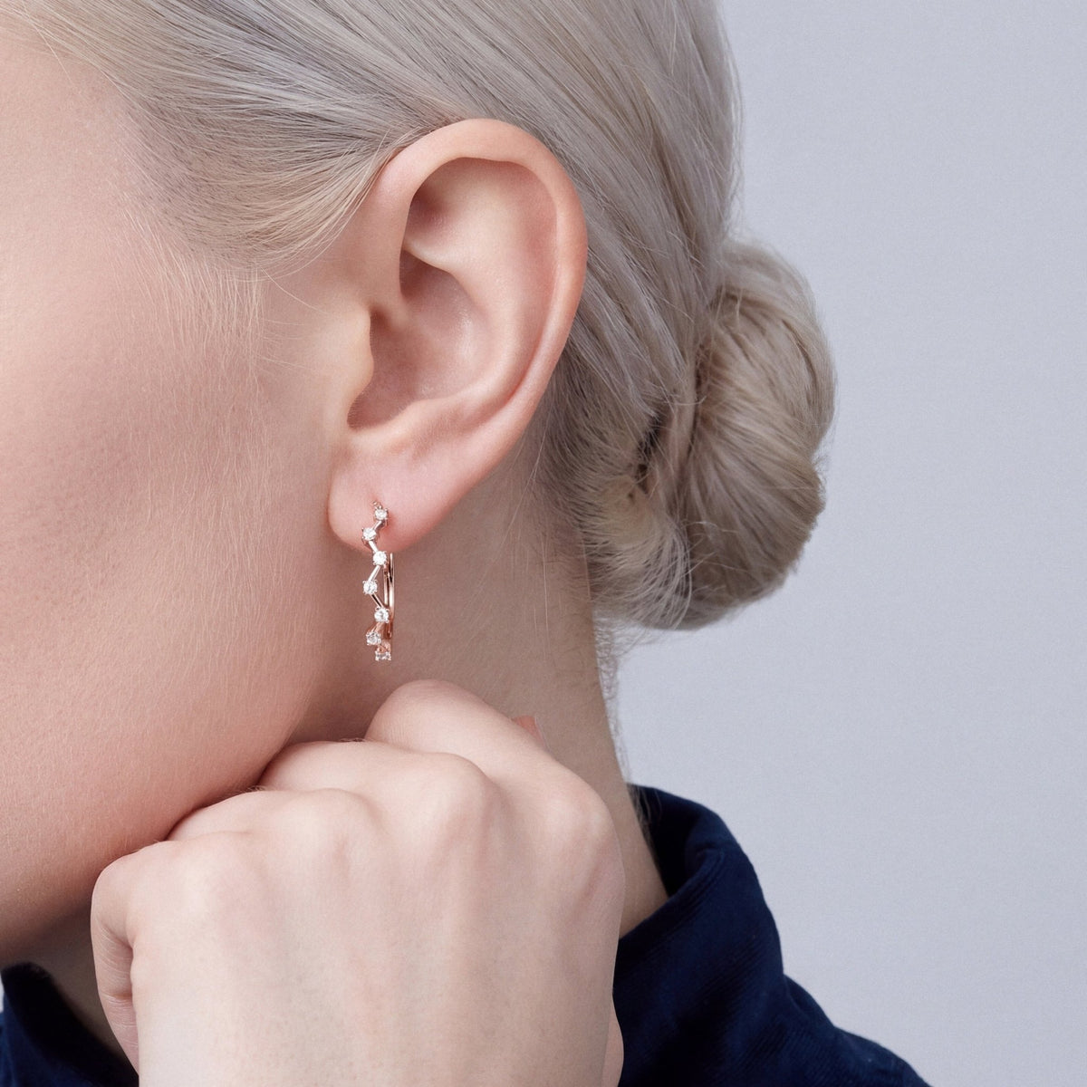 Woman in a midnight-navy velvet mock neck wearing a natural diamond zigzag hoop earring in 14K rose gold